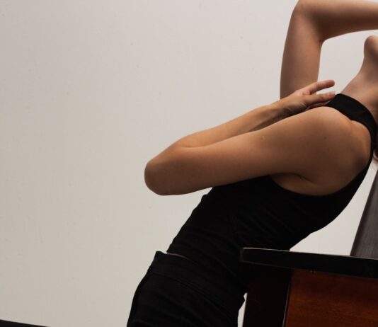 오늘도 앉아있는 당신을 위한 “의자 요가” woman in black tank top and black pants sitting on brown wooden table