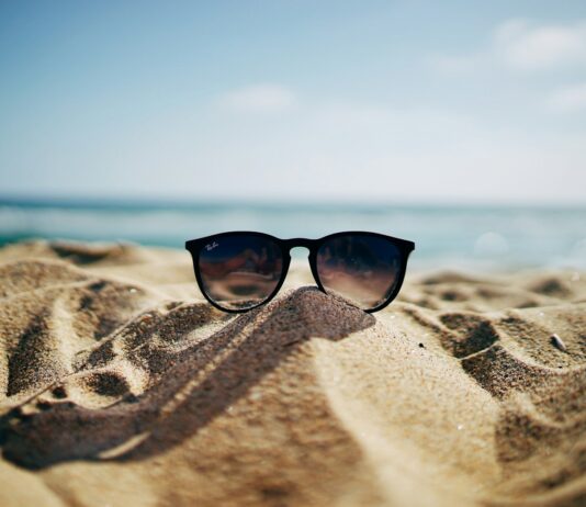 초여름, 건강을 지키는 방법들 black Ray-Ban Wayfarer sunglasses on beach sand