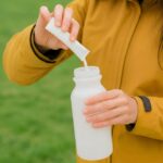 “영양, 식탁 만족에서 시작”… 보충제 현명하게 활용하는 생활 습관 Person pouring powder into a water bottle