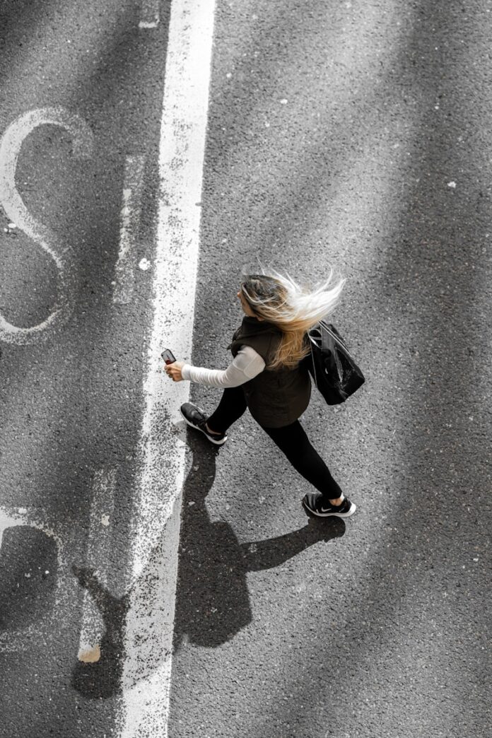 Photo by Krzysztof Hepner woman in black jacket and black pants walking on gray asphalt road during daytime